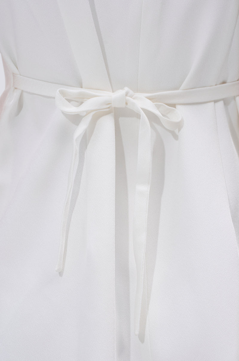 Close-up of the back of the A LA MODE MINI BLAZER DRESS IN WHITE, featuring a fabric belt tied in a neat bow at the waist. The smooth material showcases elegant soft folds and a bright, clean finish.