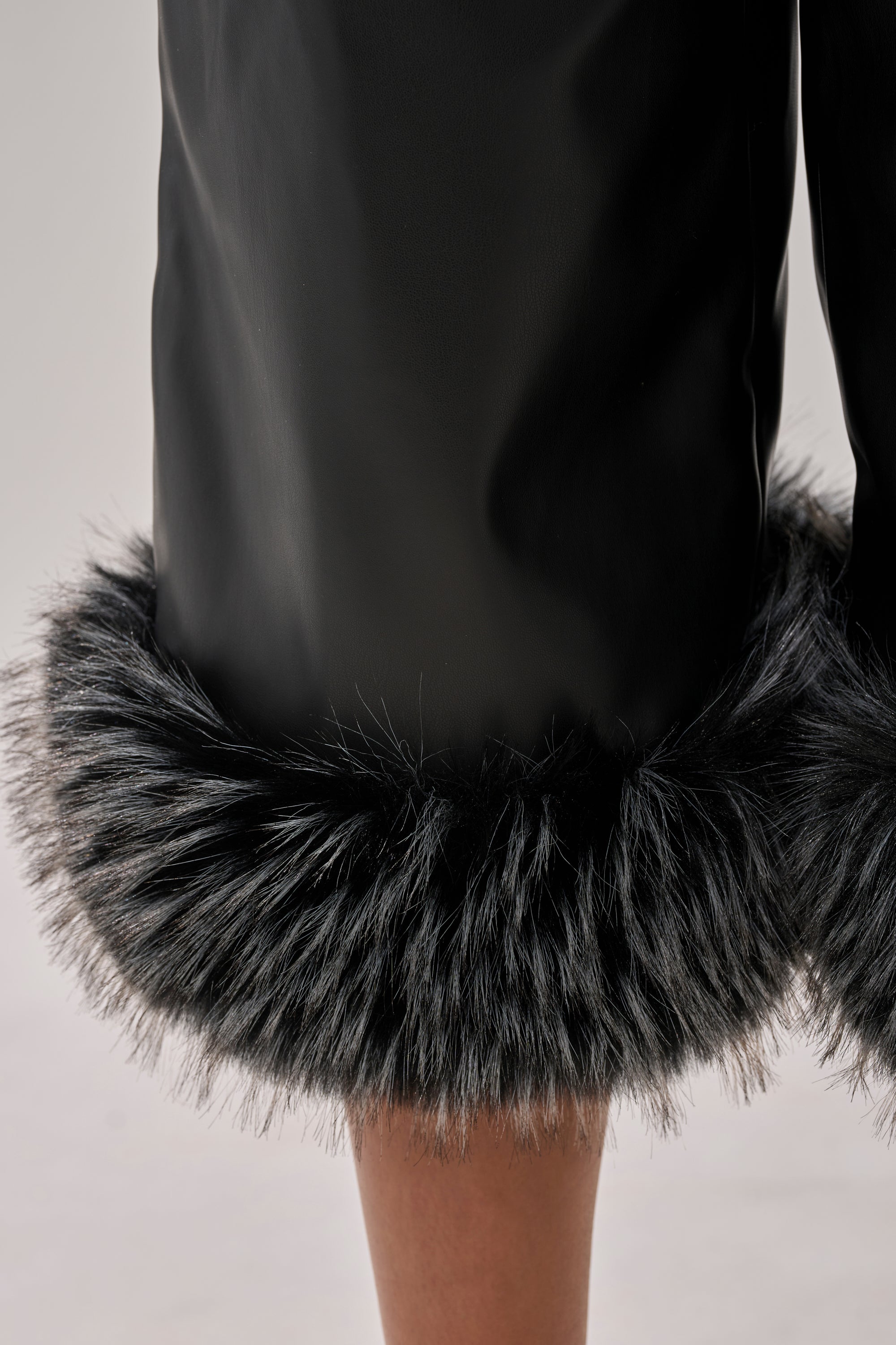 A close-up of the lower part of the MIND YOUR OWN FUR TRIM BERMUDA SHORTS, showcasing wide, fluffy gray faux fur trim at the hem against a neutral background.