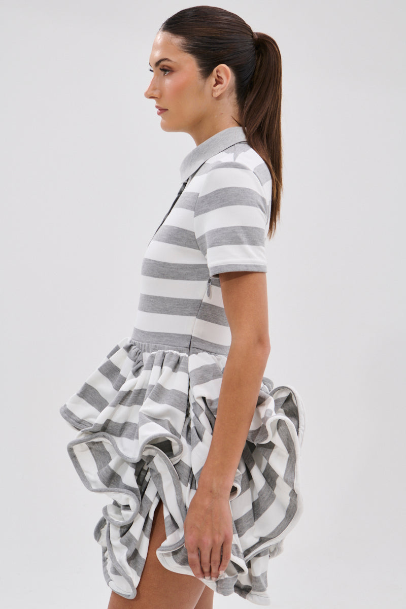 A woman with a sleek ponytail models the OFFICE SIREN STRIPED SHIRT DRESS, a gray and white striped shirt dress with short sleeves and a ruffled bubble skirt, shown in profile against a plain white background.