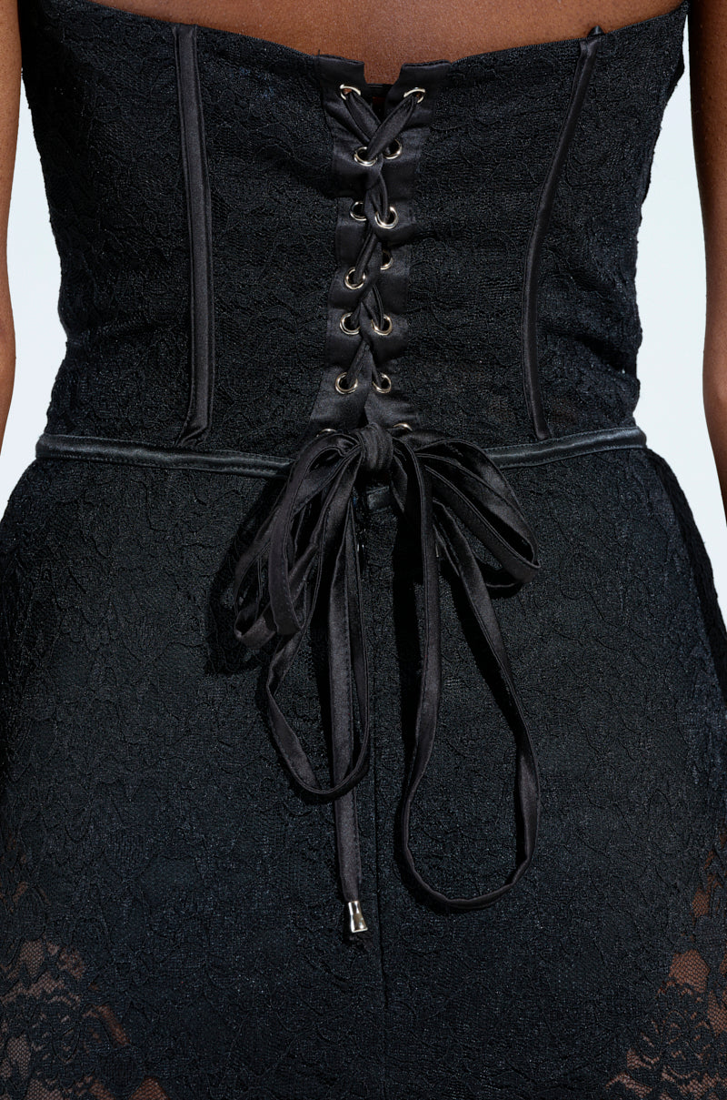 Close-up of the TRENDSETTER LACE MAXI DRESS in black lace, featuring a corset with lace-up back and waist bow. Its delicate pattern enhances the strapless silhouette, making it ideal for any occasion.