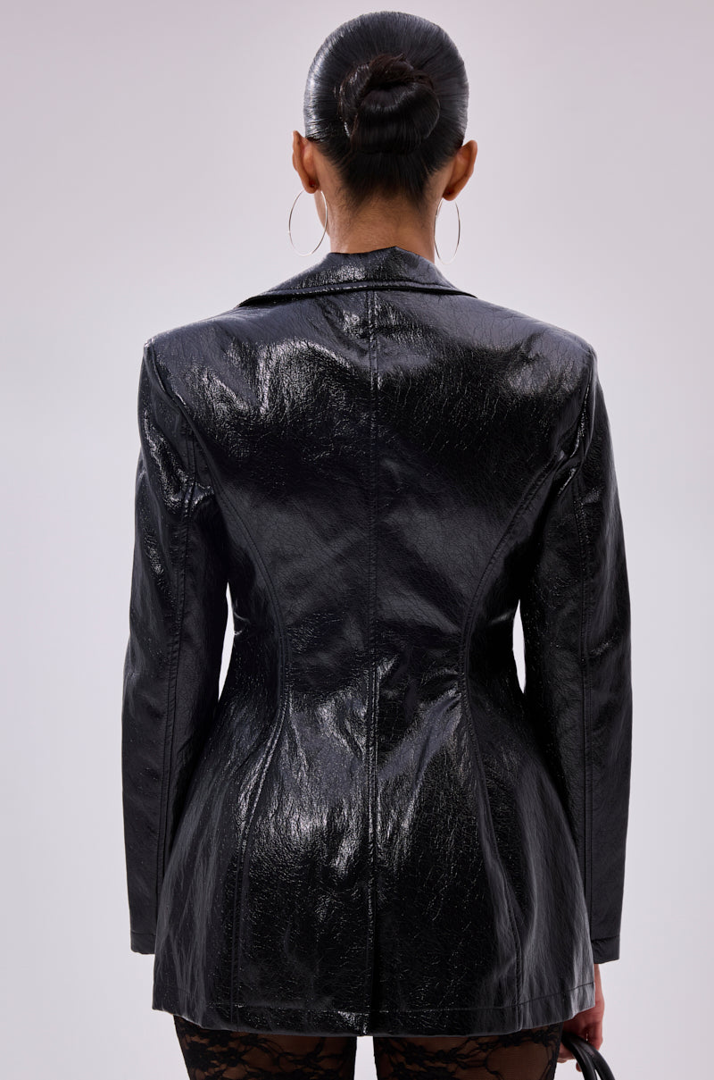 A person with dark hair in a sleek bun and large hoop earrings models the HERE FOR THE DRAMA PEBBLED BLAZER, featuring a longline silhouette, shown from the back against a plain light background.