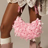 A white lace dress and pink boots outfit is accessorized with the BOWTIFUL PURSE, adorned with baby pink bows. Knee-high ribbed socks complete the look, while the top handle bag dangles elegantly from a hand against a neutral background.