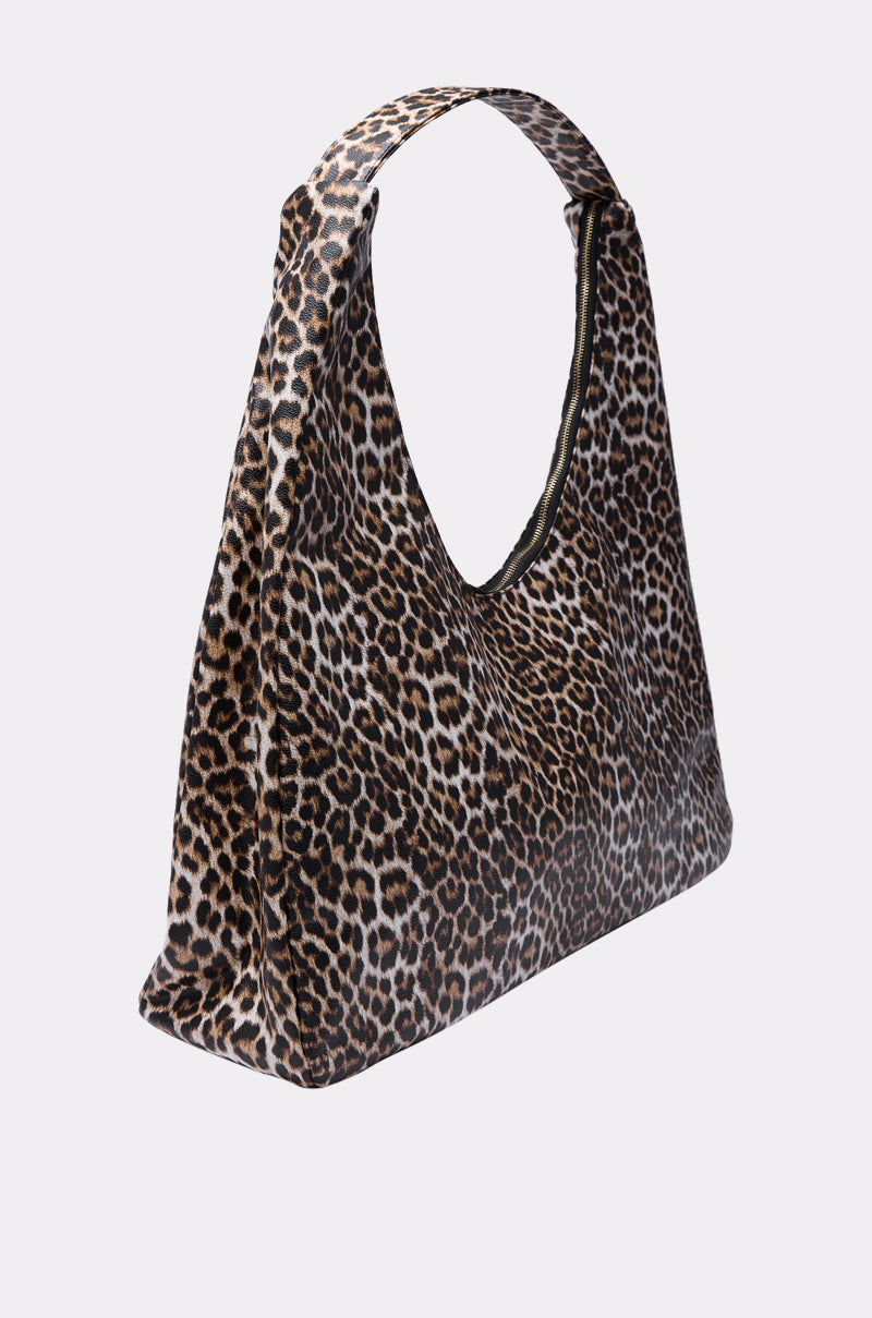The WILD ONE PU OVERSIZED TOTE, a triangular leopard-print bag with a wide strap made from faux leather, stands out against a plain light gray background.