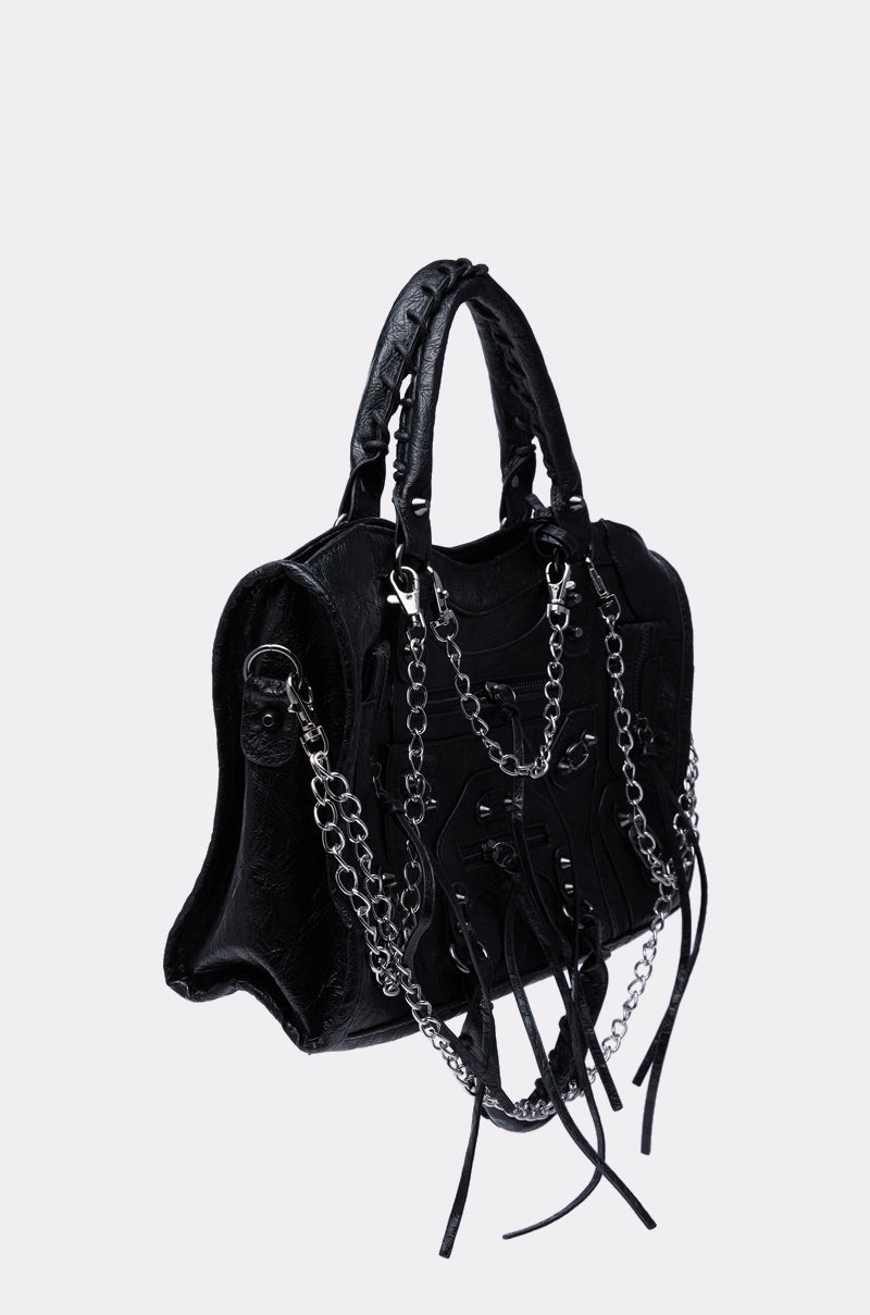 The YOUR LOSS PURSE is a black edgy handbag with embossed patterns, silver chain strap details, metal hardware, and long leather tassels, shown against a plain light gray background.