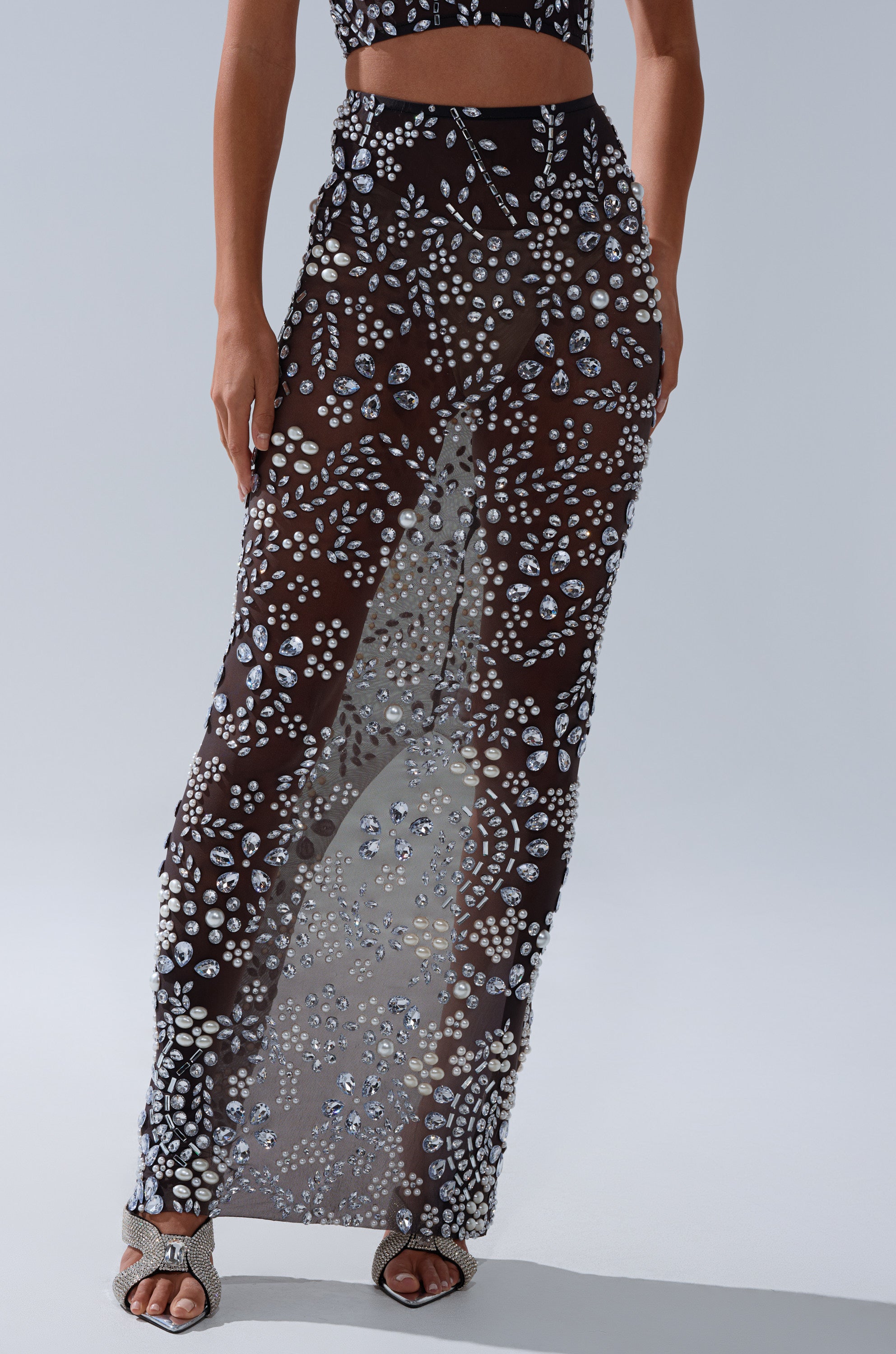 Only the lower torso and legs are visible, wearing the BLING BLING MESH RHINESTONE MAXI SKIRT—high-rise fit, adorned with sparkling white and silver embellishments—paired with silver open-toe heels.