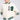 A person in a BETTER LUCK NEXT TIME EMBELLISHED BOMBER, an oversized white varsity jacket with green striped accents and the number "19" adorned on it. The sleeves feature pearl rhinestone details. They also wear sunglasses, a light pleated skirt, and have neatly styled blonde hair.