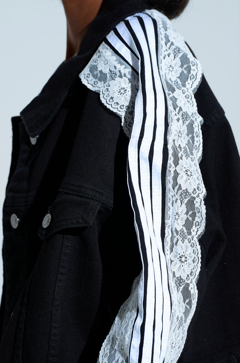 The Dylan Lace Detail Denim Jacket features a black, dark wash design with floral lace and striped accents on the shoulders, front silver buttons, and metallic button cuffs for elegance.