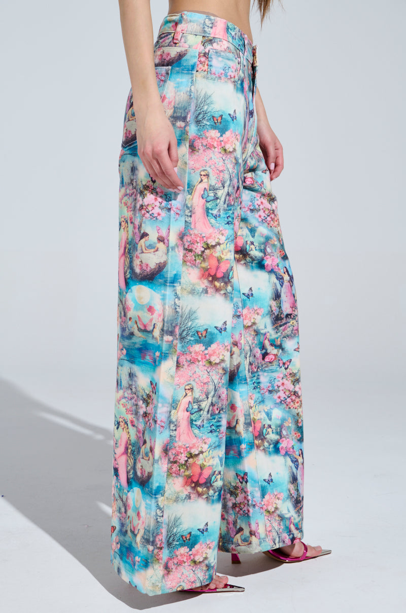 Someone wearing FEMALE FANTASY PRINTED DENIM PANTS features candy-colored, artistic scenes in pastel tones, paired with pink open-toe heels. The high-waisted wide-leg design creates a dreamy look where only the lower half of the body is visible.
