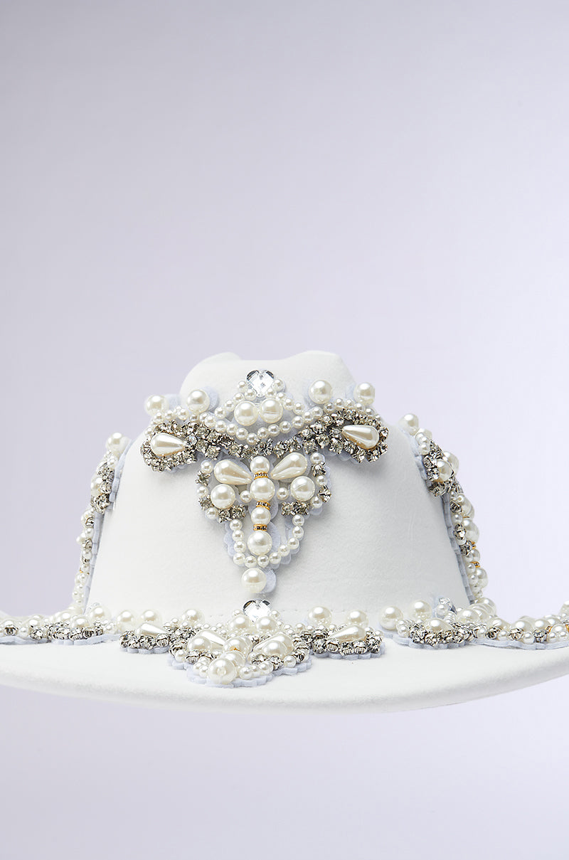 The BOUJEE PEARL COWBOY HAT is an elegant headpiece with intricate beadwork and rhinestone accents, featuring pearls and silver embellishments in ornate patterns against a plain background.