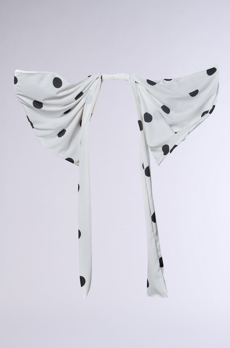 The POLKA DOT IT HAIR BOW, shown against a plain light background, features white fabric with large black polka dots and long front ties styled into an oversized bow.