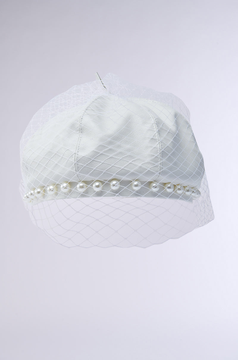 The EDITORIAL BERET features a white hue, adorned with a pearl-embellished trim and a netting overlay that extends gracefully beyond the brim, offering a delicate, textured layer to this classic design.