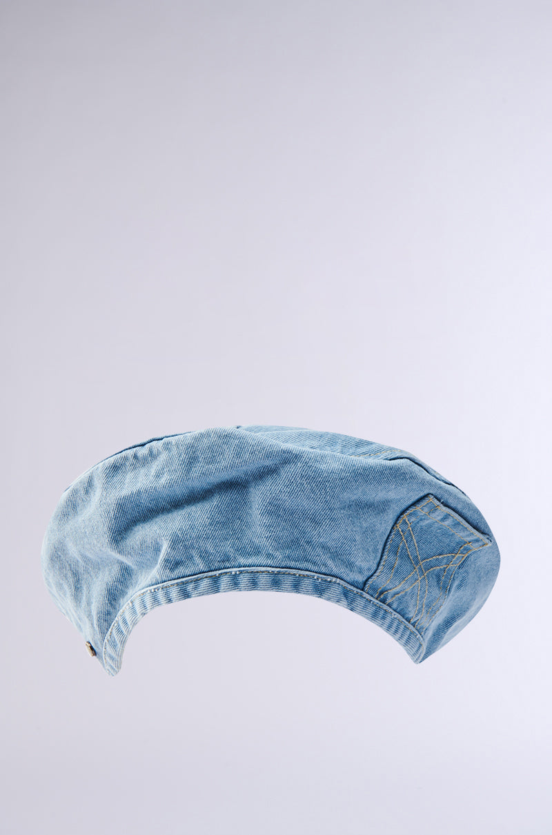 The IT GURL DENIM BERET by AKIRA Label features visible stitching in light blue denim and is displayed against a plain, light gray background—a chic accessory for any modern wardrobe.
