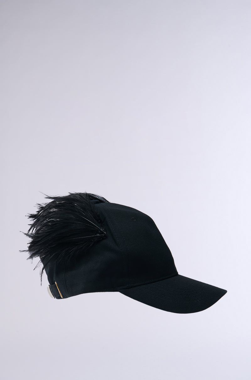 The BRB FLYING AWAY HAT is a stylish black cotton ball cap with plume of black feathers elegantly attached to the back, featuring an adjustable strap closure. Displayed upright against a plain white background, it showcases its unique design.