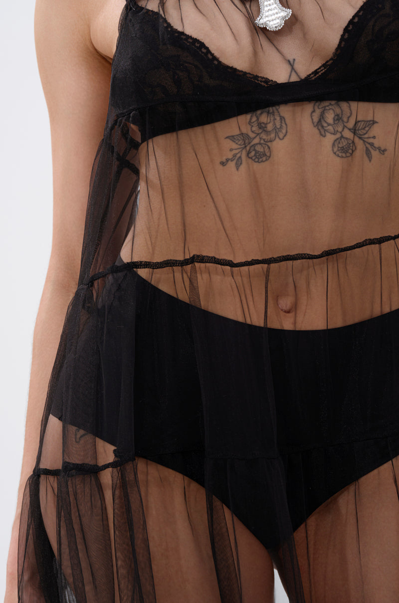 A person wears the PERFECT FOR LAYERING TULLE MAXI DRESS, styled to showcase its sheer black mesh fabric and intricate chest tattoo, paired with black high-waisted underwear for a modern, textured look.