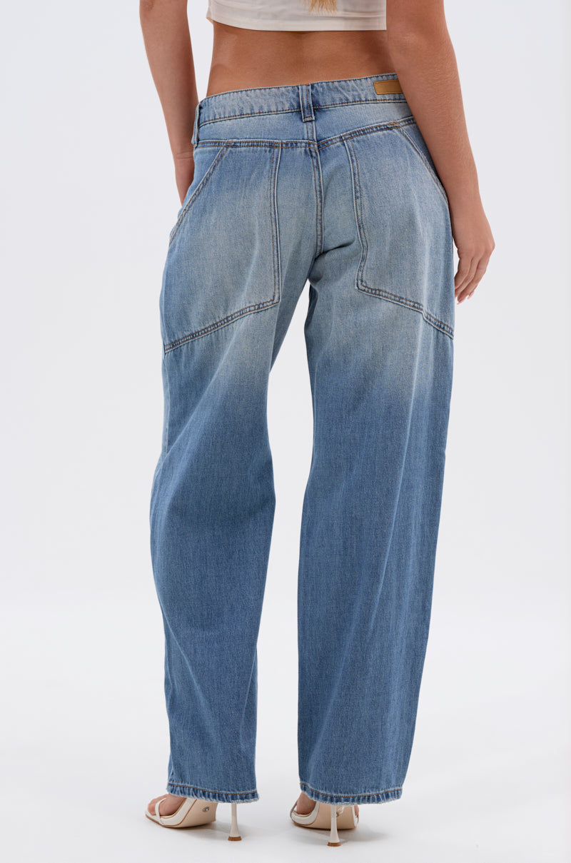 A person shown from the back wears RELAX WITH ME WIDE LEG DENIM, 100% cotton vintage wash jeans with visible seams and large back pockets, paired with a beige crop top, standing on a white background.