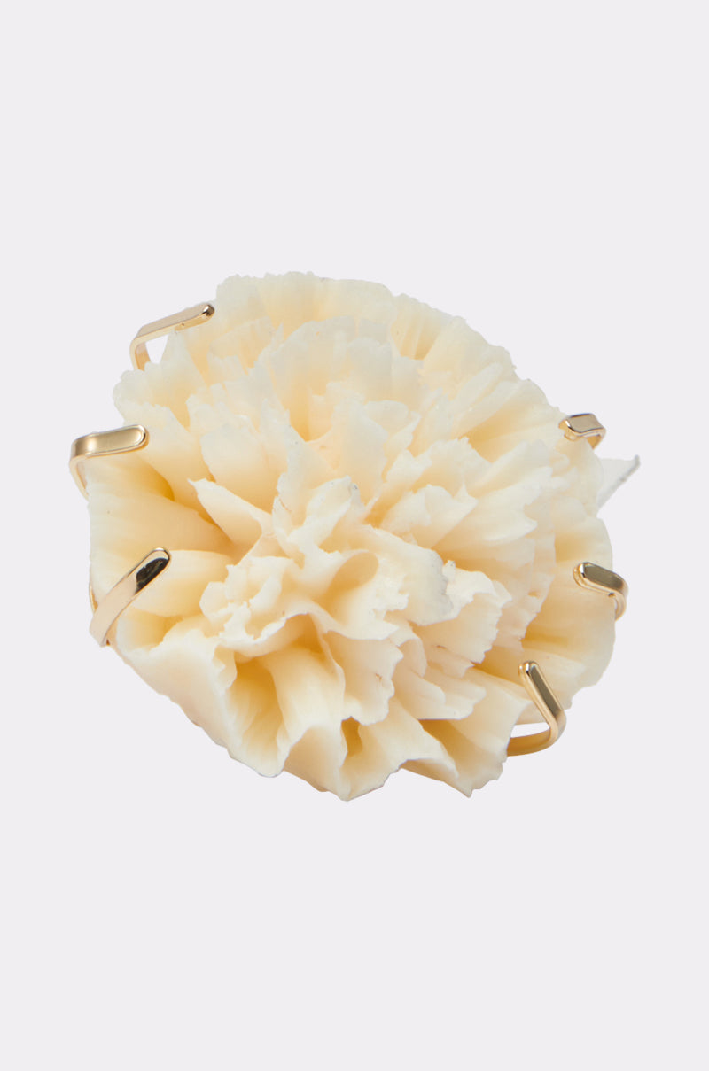 The IN BLOOM RING features a cream-colored, flower-inspired design secured with gold prongs—a striking statement accessory that stands out against a plain white background.
