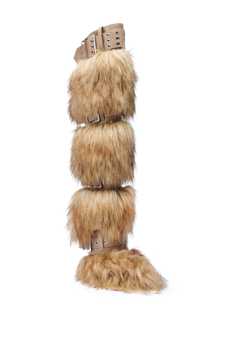 The AZALEA WANG AMALBERT BROWN MULTI FUR AND BUCKLES BOOT is a tall, knee-high boot with brown faux fur sections, tan straps with buckles, and a pointed toe, resembling an animal leg.
