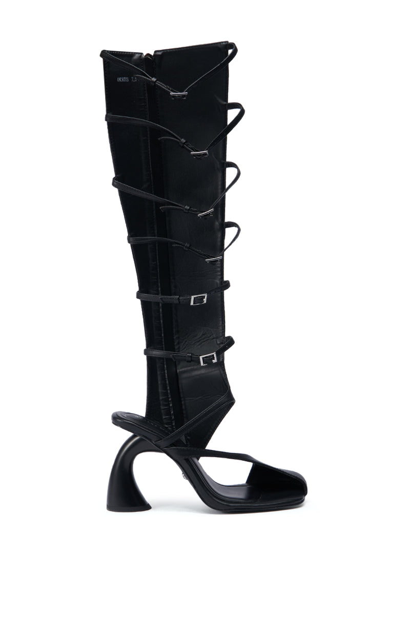 Introducing the AZALEA WANG ANDRIUS BLACK GLADIATOR SANDAL: a high-fashion knee-high boot, expertly crafted from faux leather, featuring an open-toe design and a distinctive curved heel. This unique piece showcases multiple straps with buckles along its length, echoing the style of a modern gladiator sandal.