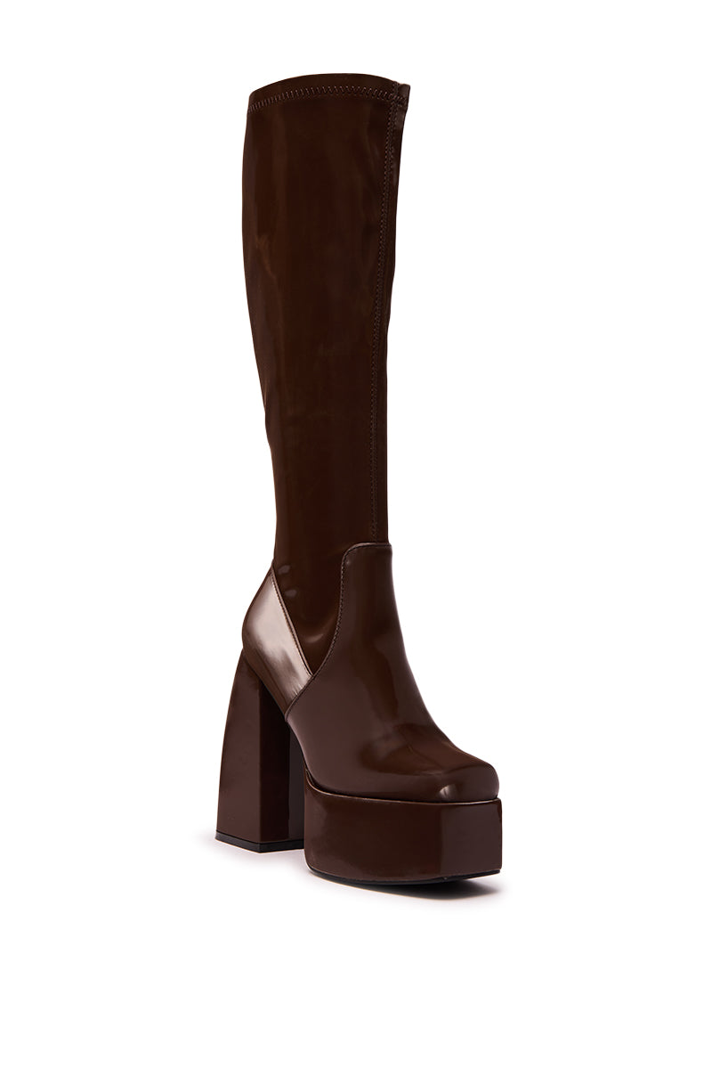 The AZALEA WANG AURON BROWN LIQUID LUXE PLATFORM BOOT is a tall, knee-high, shiny dark brown faux patent leather boot with a chunky high heel and rounded toe, displayed at a slight angle on a white background.