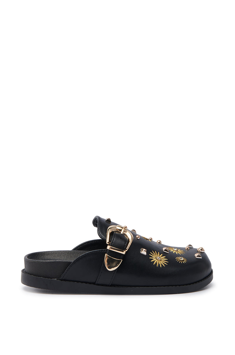 The AZALEA WANG TROUVER BLACK GOLD STARBURST FLAT is a black slip-on mule featuring an almond toe, gold buckle, sunburst embroidery, and metallic studs on a faux leather upper.