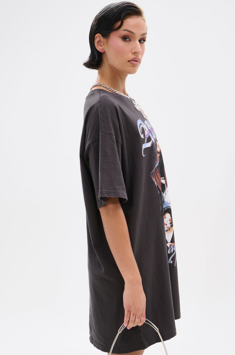 A woman with short dark hair confidently models the AALIYAH FOREVER GRAPHIC TSHIRT DRESS, styled with a metallic handbag and chunky chain necklace—ideal for adding pop icon flair to your streetwear lineup.