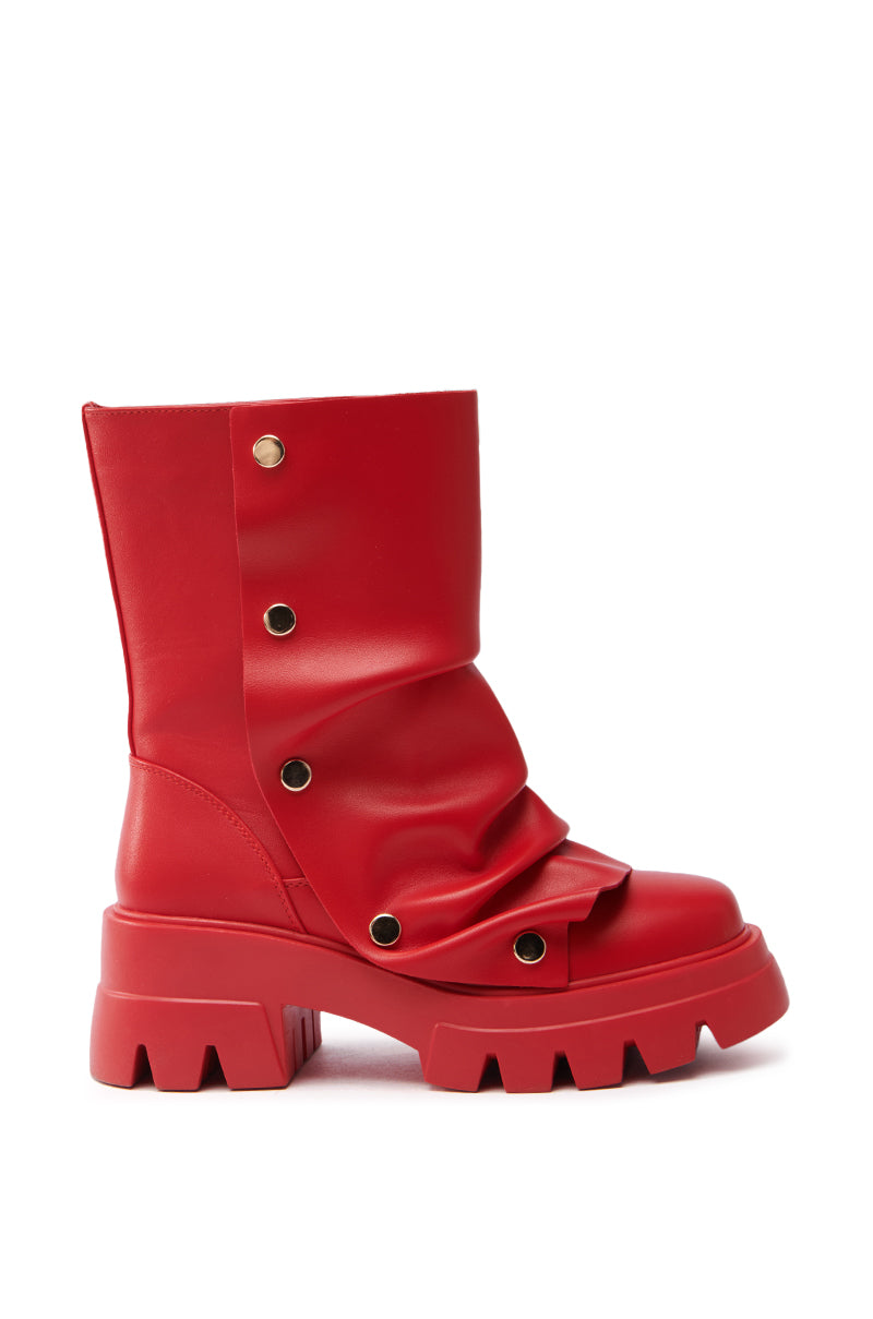 The AZALEA WANG BHARTI RED SNAP DETAIL BOOTIE is a red faux leather bootie with a chunky sole and vertical decorative gold rivets. It boasts a slouched design for a unique, bold look.