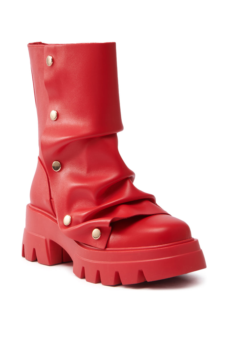 The AZALEA WANG BHARTI RED SNAP DETAIL BOOTIE is a bold red faux leather bootie featuring wide folds along the shaft, metallic studs, and a chunky textured platform sole for a rugged look. The image shows both side and front views.