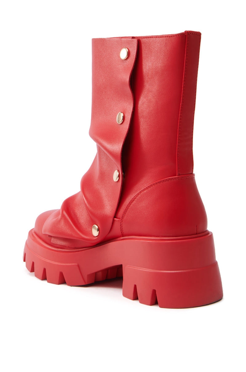 The AZALEA WANG BHARTI RED SNAP DETAIL BOOTIE features a chunky platform sole with deep treads, gold side snap buttons, and a mid-calf height. It has a slightly slouched design in red faux leather with a smooth, glossy finish.