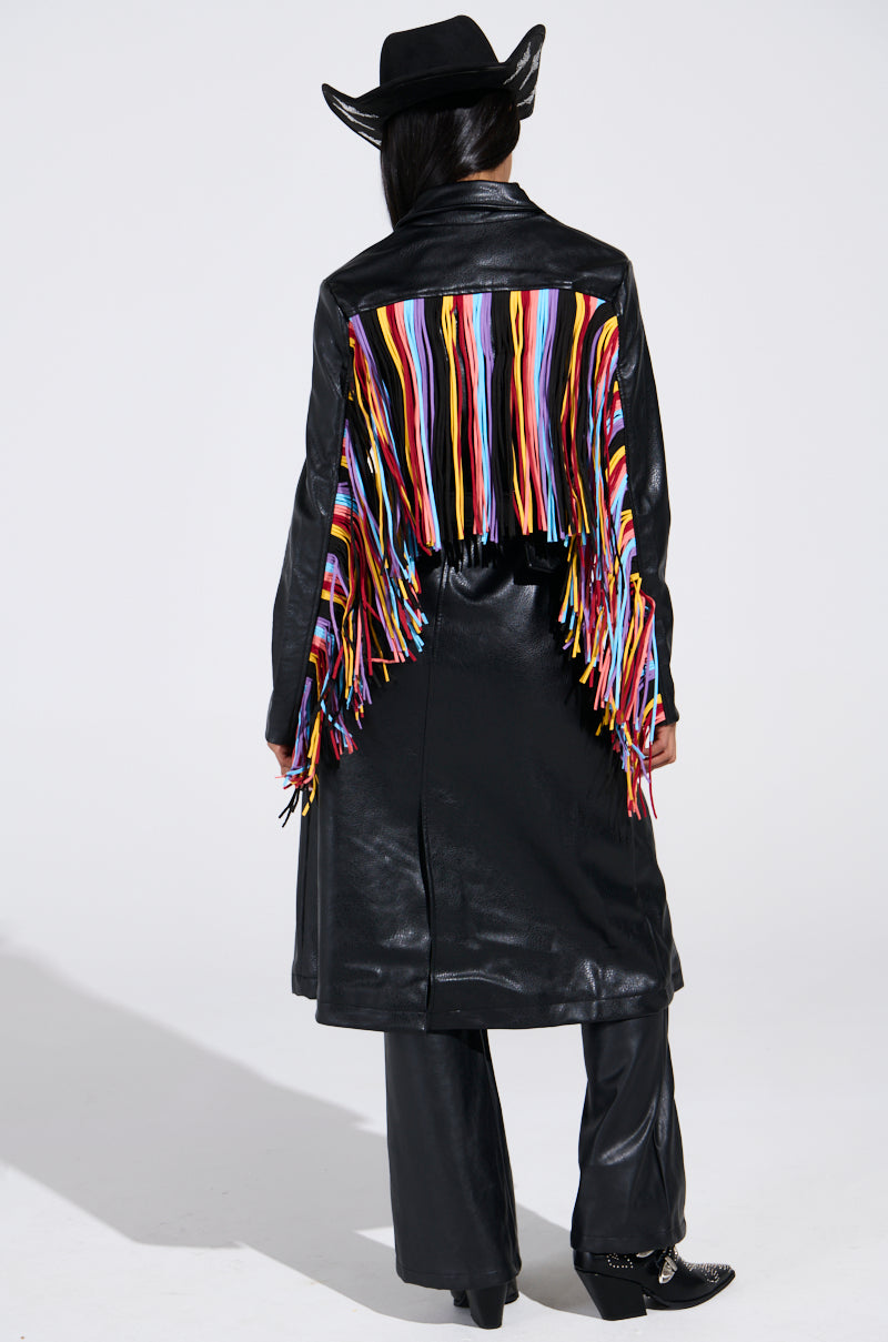 A person in a black cowboy hat and the RYDER FRINGE TRENCH IN BLACK MULTI with multi-color fringe on the back stands facing away from the camera against a plain white background.