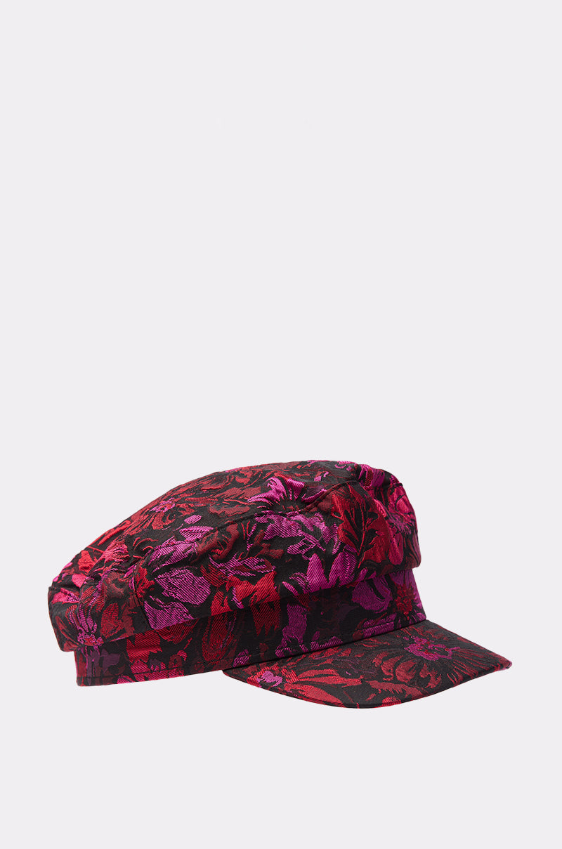 The LUXE LIVING BRIM HAT is a stylish floral brocade newsboy cap featuring vibrant red, pink, and purple tones on a black background, shown against a plain white surface.
