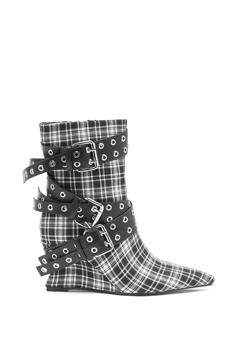 The AZALEA WANG CHALKIS Black White Plaid Buckle Wedge Bootie features a black-and-white plaid pattern, pointed toe, three black straps with silver eyelets and buckles, and a low wedge heel.