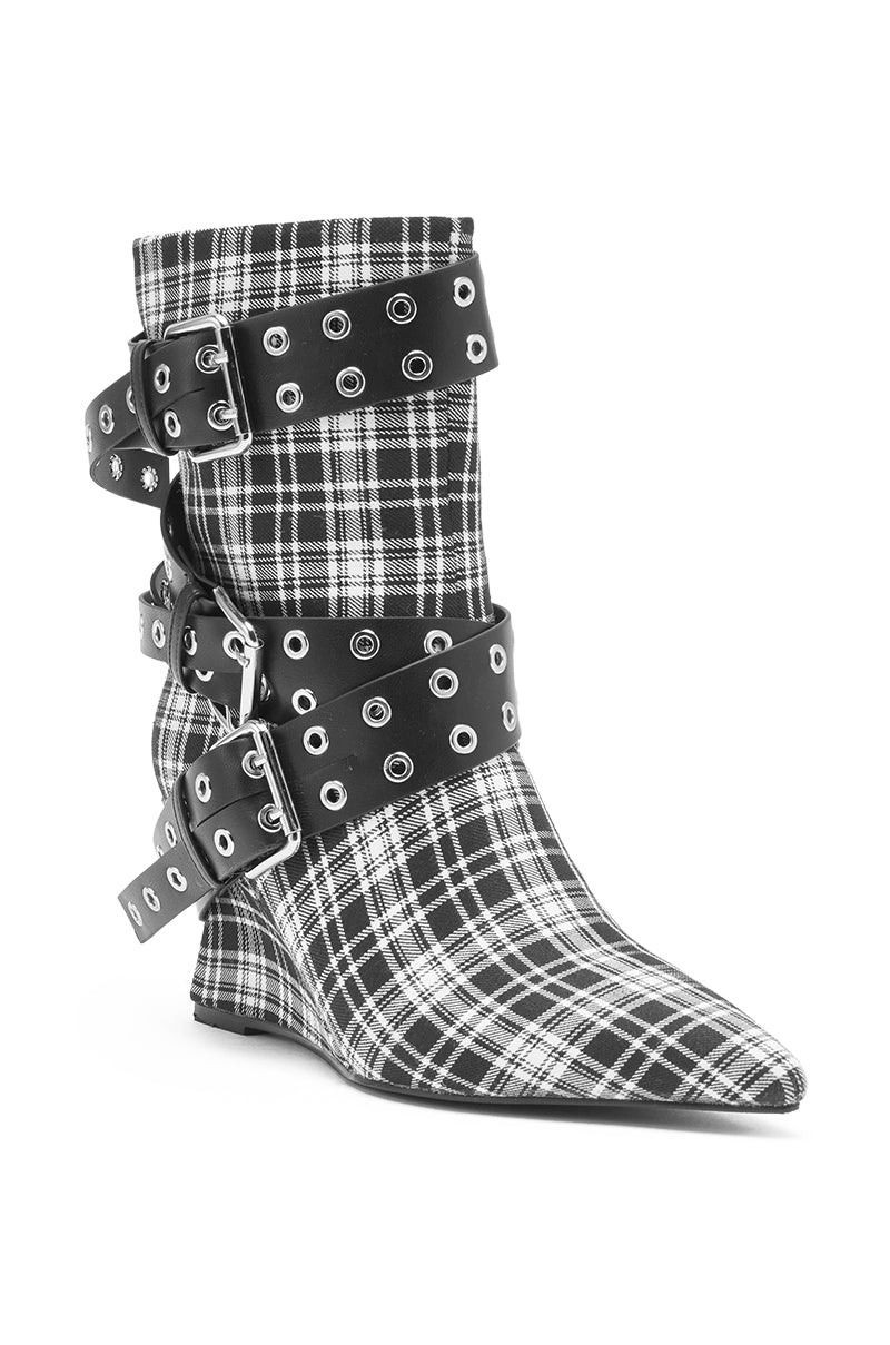 The AZALEA WANG CHALKIS BLACK WHITE PLAID BUCKLE WEDGE BOOTIE is a pointed toe bootie with a black and white plaid pattern, finished with three black straps featuring silver eyelets and large silver buckles for a bold look.