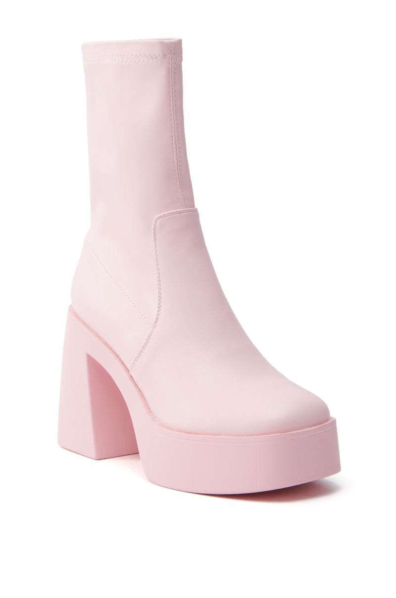 The AZALEA WANG DANIELLE bootie in baby pink stretch PU features a chunky high heel, ankle-length design, and smooth faux leather with a rounded toe for a trendy and bold look.