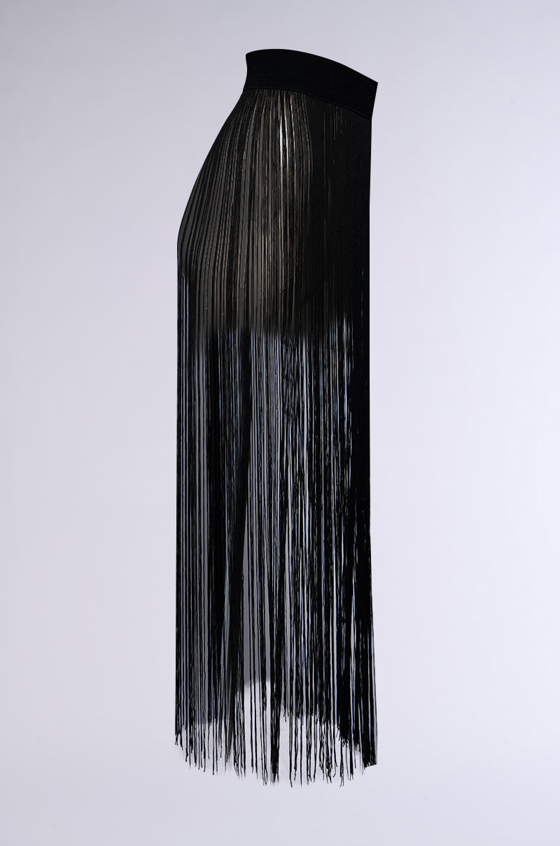A side view of the SO FREE FRINGE BELT SKIRT showcases its cascading fringe detail, with long, thin strands extending from the elasticated wide waistband to the hem. The flowing, textured appearance is beautifully accentuated against a neutral background.