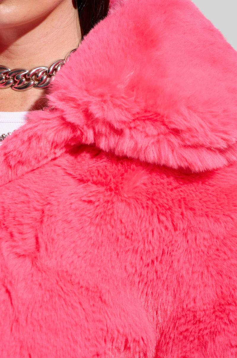 Close-up of a person wearing the DREW FAUX FUR BOMBER IN HOT PINK, featuring a large collar. A chunky silver chain necklace is partially visible, providing metallic contrast to the soft texture and cropped silhouette of the jacket.