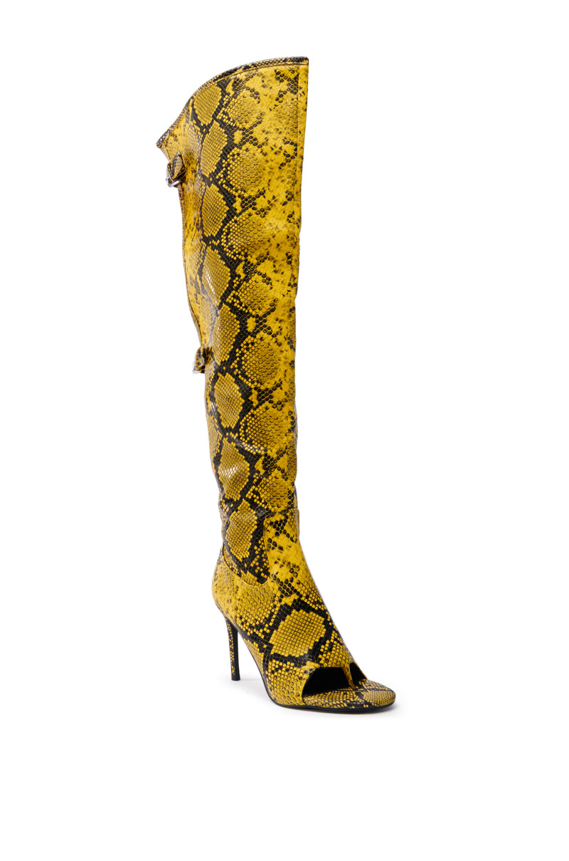 The AZALEA WANG ELIAM BOOT IN YELLOW is a yellow and black thigh-high shaft boot featuring an open toe and stiletto heel, made from faux snakeskin leather with a sleek, textured design for a bold fashion statement.