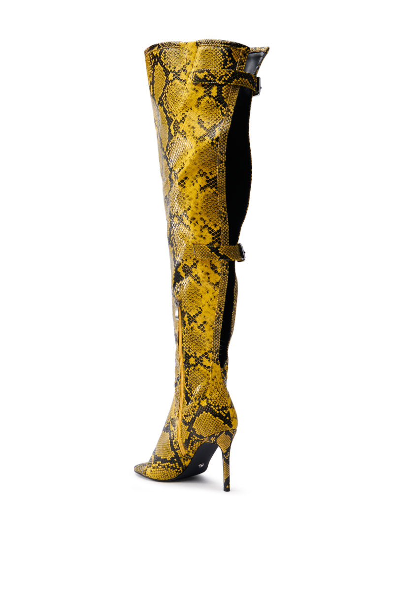 The AZALEA WANG ELIAM BOOT IN YELLOW is a striking over-the-knee boot with a yellow and black faux snakeskin pattern, featuring a pointed toe and stiletto heel, displayed against a plain white background to highlight its thigh-high shaft.