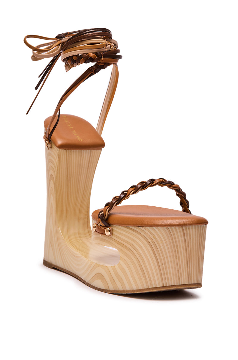 The AZALEA WANG FANTASA BROWN HALLOW PLATFORM WEDGE STRAPPY SANDAL features a wood-textured platform, open toe, braided leather ankle-tie straps, and a unique heel cutout for a modern look.