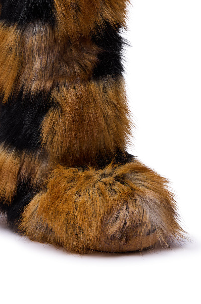 A close-up of the AZALEA WANG FENNEC MULTI PATCH WORK FUR KNEE HIGH BOOT, featuring a furry, tiger-striped pattern in orange, black, and brown against a white background.