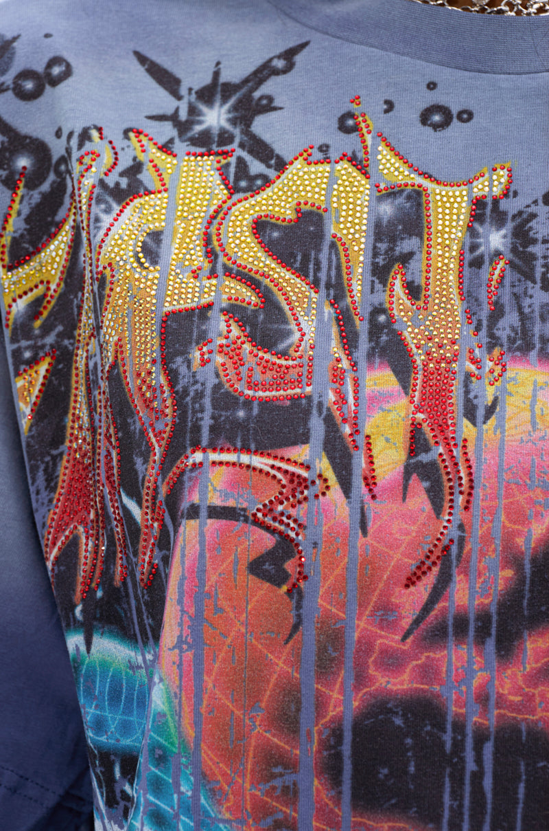 Close-up of the IRREVERENT OVERSIZED GRAPHIC TEE, showcasing bold abstract graffiti-style text with yellow and red accents, rhinestone details, and colorful dripped paint patterns in the background.