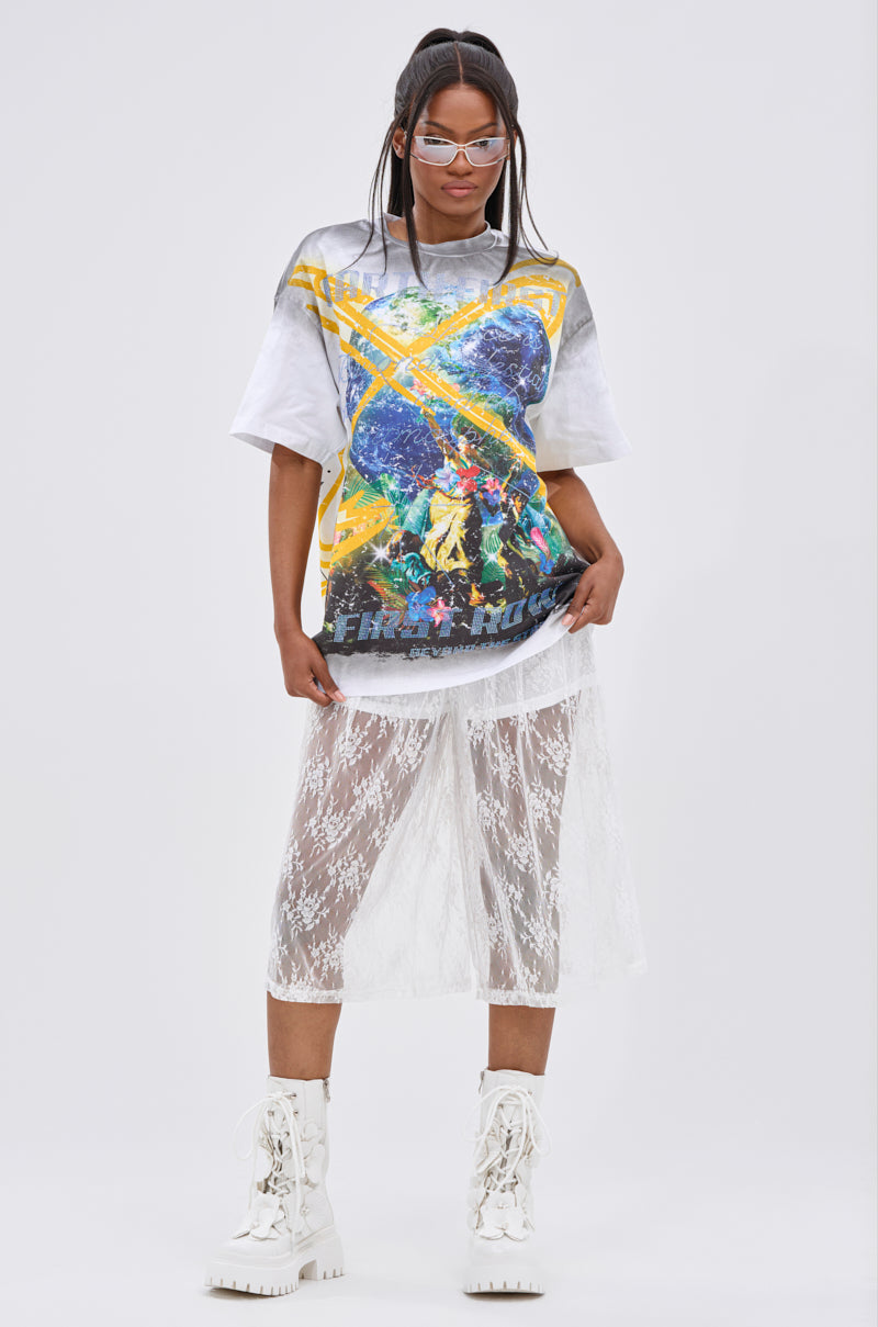 Wearing the NEW WORLD OVERSIZED GRAPHIC TEE with a planetary motif, sheer lace skirt over shorts, white lace boots, glasses, and straight hair, she stands confidently against a plain background for a streetwear-inspired look.
