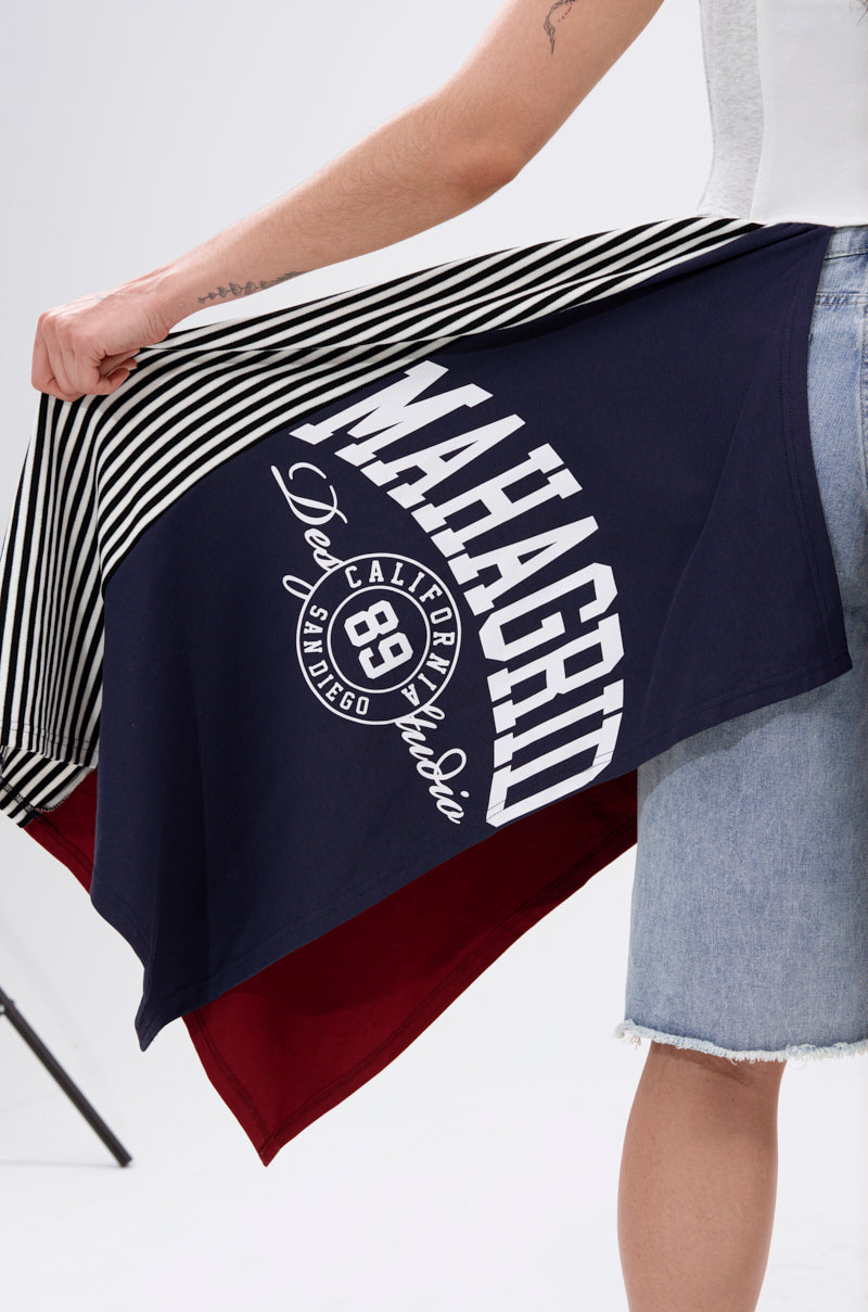 Wearing the LIGHTS OUT PATCHED UP JERSEY CORSET, a person in denim shorts and an upcycled collegiate tee holds open a navy striped jacket with "MAHAGRID" on the back and a deep red inner lining.