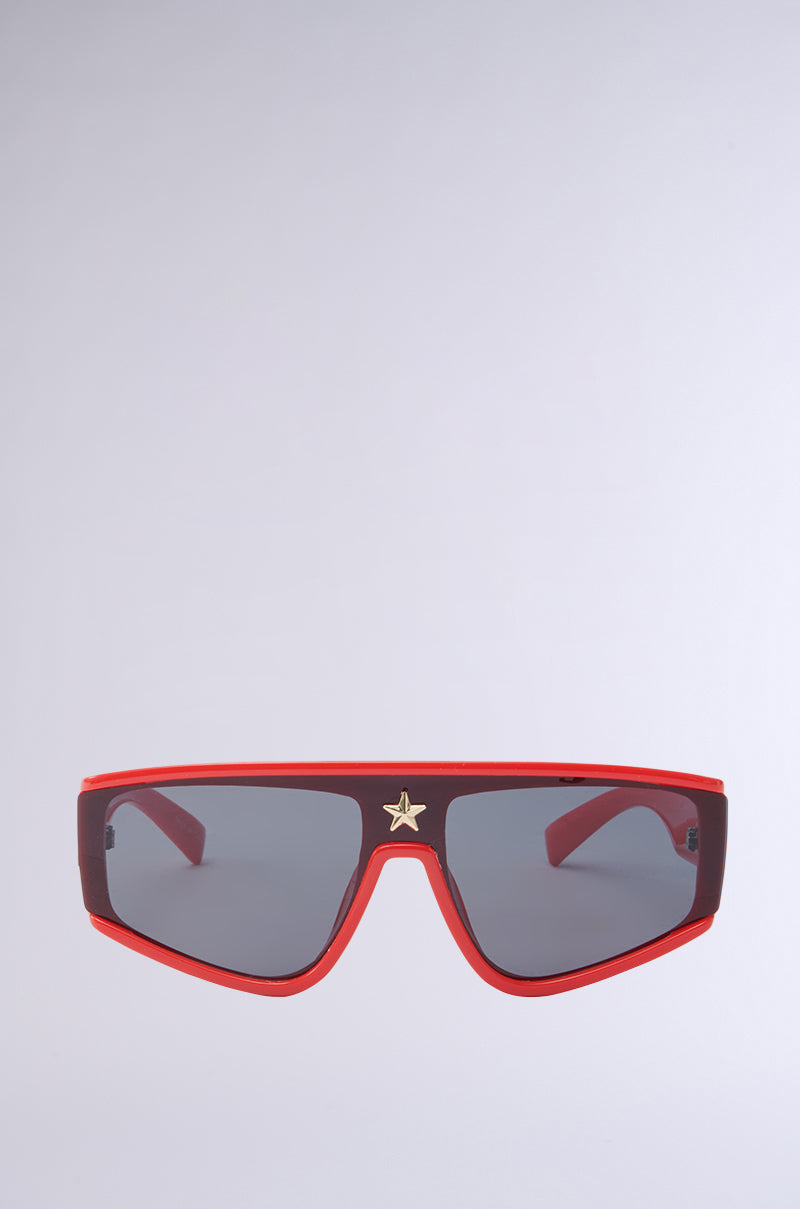 RED HOT SUNGLASSES, featuring a red frame, dark-tinted lenses, and a star emblem on the bridge, have a bold monobrow silhouette and structured shape. Set against a plain, light background, they truly stand out.