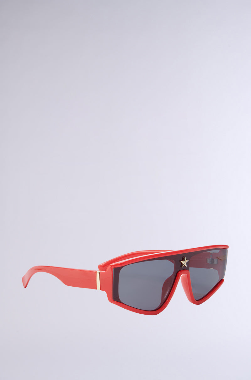 RED HOT SUNGLASSES feature angular frames, dark lenses, and a small star design in the top corner for added flair. The bold monobrow silhouette contrasts against a plain light gray background.