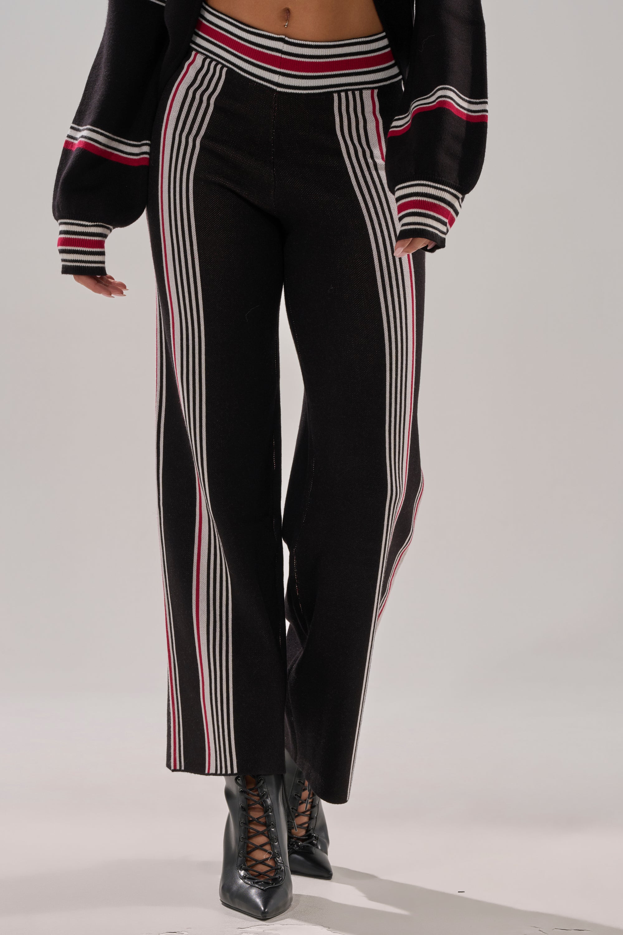 Wearing the KENDALL SWEATER WIDE LEG PANT with black lace-up heeled boots and a matching jacket, a person stands against a plain background.