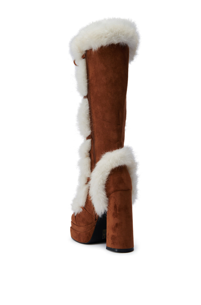 The AZALEA WANG HARIBO TAN FUR BOOT, crafted from brown faux suede, showcases a white fur trim and a chunky block heel, elegantly displayed from the back against a pristine white background.