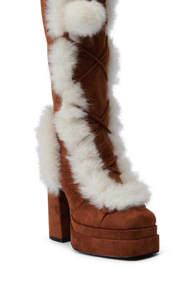 Introducing the AZALEA WANG HARIBO TAN FUR BOOT: a stylish knee-high platform boot crafted from brown faux suede, adorned with white faux fur trim and featuring a chunky high heel. This boot boasts decorative laces and a layered sole, seamlessly combining fashion with comfort.