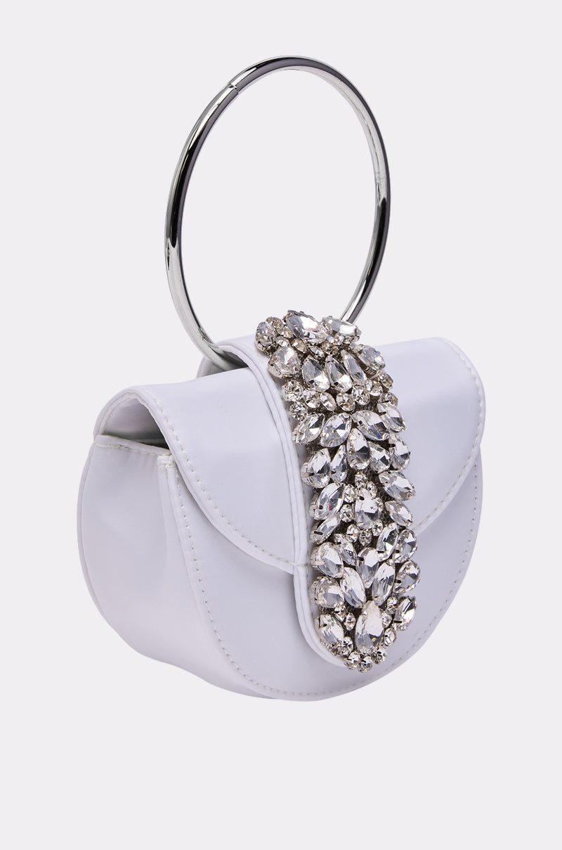 The TO THE EVENT EMBELLISHED PURSE is a small white crystal handbag with a bold silver ring handle and a rhinestone-adorned flap—an eye-catching accessory perfect for special occasions.