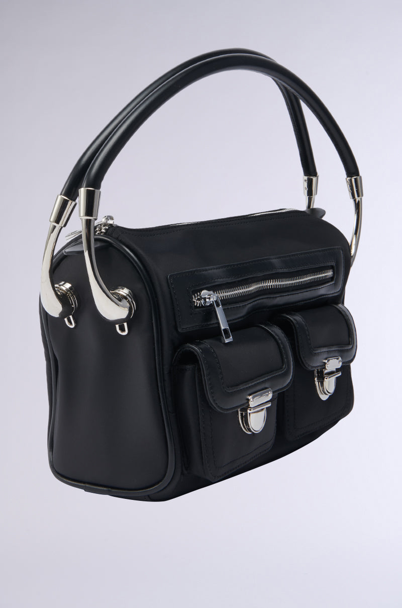 The REALLY LIKE THAT PURSE is a black leather, utility-inspired bag with silver hardware, zippered and two buckle pockets on the front, plus sturdy double handles, shown against a light gray background.