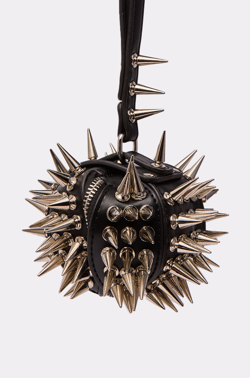 The IM SHARP MINI BAG, a small black faux leather handbag with large metallic spikes on the body, zipper, and handle, is displayed against a plain white background.